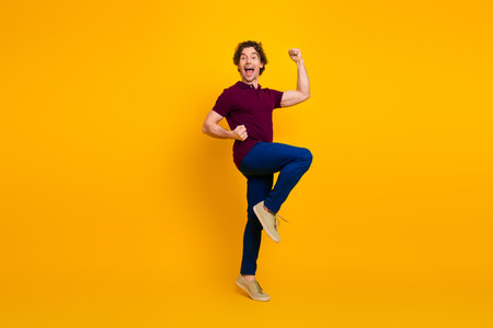 Excited young man in casual outfit celebrating and posing against bright yellow background with enthusiastic expressionの写真素材