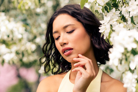 Gorgeous woman enjoying a sunny spring day surrounded by blooming flowers in a botanical gardenの写真素材