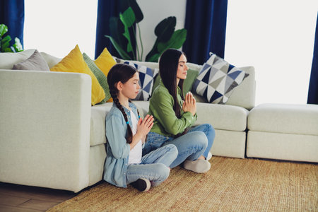 Mother and daughter sitting on the carpet in their cozy living room, bonding and spending quality time togetherの写真素材