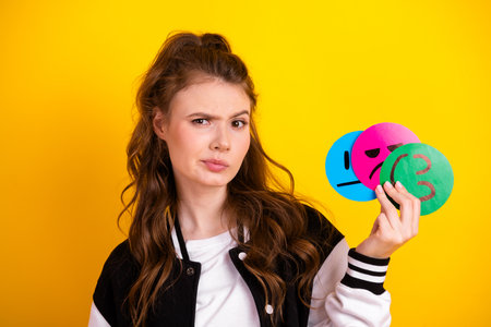 Student Expressing Emotions with Colorful Faces Against Yellow Background in Casual Outfitの写真素材