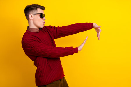 Cheerful Young Man in Casual Sweater Posing Against Yellow Background Showing Gestures With Hands