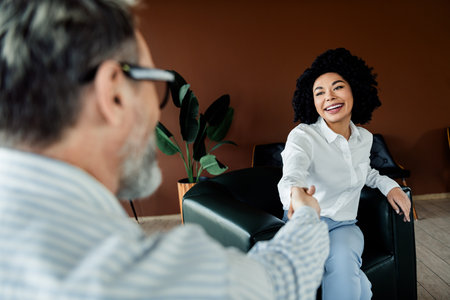 A professional woman shaking hands in an elegant office setting showcasing partnership and business collaborationの写真素材