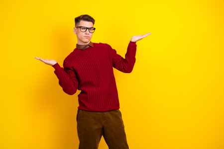 Portrait of a Young Man in Red Sweater Showing Gestures on a Vibrant Yellow Backgroundの写真素材