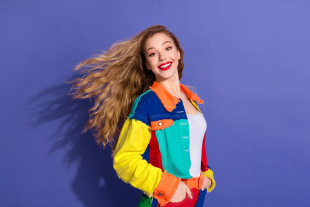 Cheerful young woman posing confidently in a colorful casual jacket with her blond hair flowing, set...