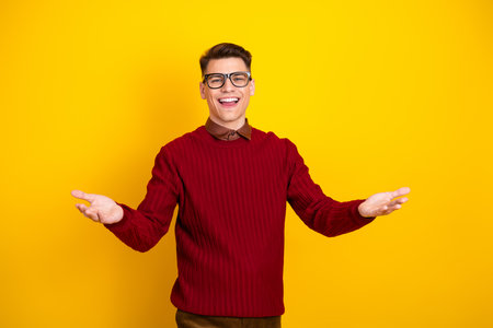 Portrait of a Happy Young Man in Stylish Red Sweater on Yellow Backgroundの写真素材