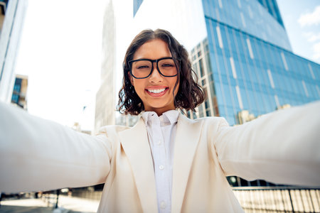 Confident businesswoman in professional attire poses outside modern skyscrapers, showcasing leadership and successの写真素材