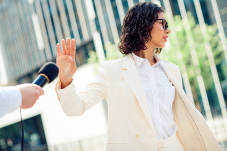 Confident young businesswoman declining a microphone during an outdoor interview in a city setting