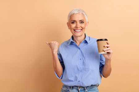 Mature Businesswoman With Stylish Short White Hair Enjoys Coffee in Fashionable Casual Attire on...