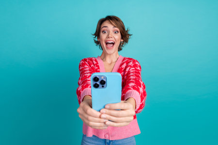 Photo of impressed funky lady wear pink cardigan communicating modern device isolated teal color...