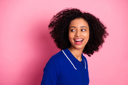 Portrait of a joyful young woman looking to the side, wearing a stylish blue polo, against a vibrant...