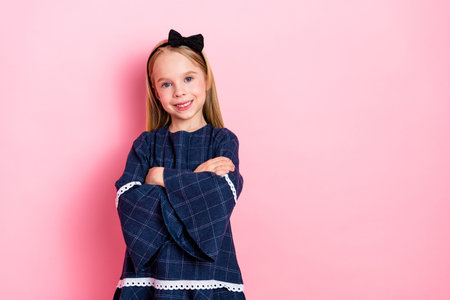 Smiling girl posing confidently against a vibrant pink background, wearing a stylish blue dress with charm and graceの写真素材