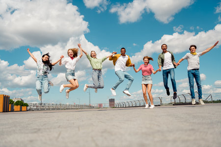 Young friends jumping outdoors during a sunny day expressing joy, unity, and togetherness