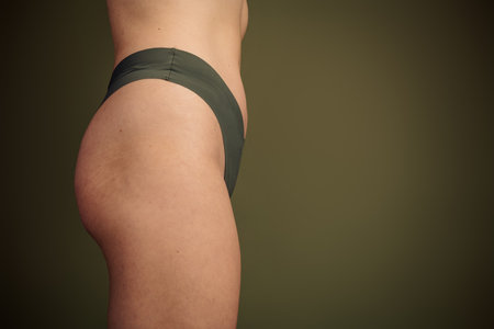 Side profile of a young woman wearing khaki lingerie on a neutral background, embracing body positivity and natural beautyの写真素材