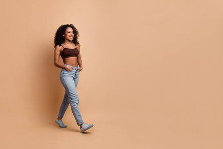 Young stylish woman enjoying casual attire in a modern beige background while expressing beauty and confidence.の写真素材