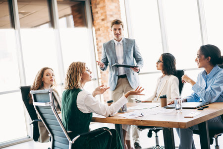 Young professionals collaborating during a business meeting in modern office setting, showcasing teamwork and corporate interactionの写真素材