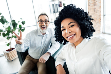 Team members taking a cheerful photo together in a bright modern office environment showcasing collaboration and diversity.の写真素材