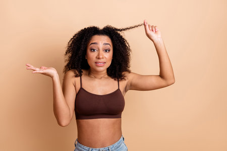 Attractive Young Woman in a Casual Outfit Posing on a Beige Background Expressing Wonder and Cumulative Cheerの写真素材