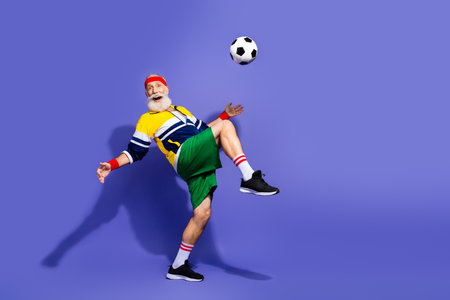Energetic senior man practicing soccer in vibrant retro sportswear showcasing active lifestyle and cheerful expressionの写真素材