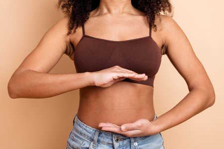 Young woman in a brown top gesturing on beige background promoting body positivity and casual style...