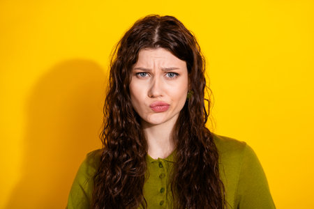 Portrait of a young, stylish woman with long curly hair making a humorous expression against a...
