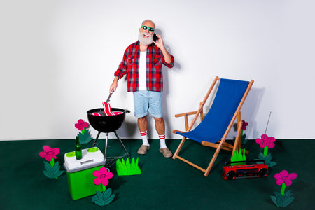 Elderly man grilling outdoors with cheerful decorations, showcasing leisure and relaxation in a colorful backyard setup.の写真素材