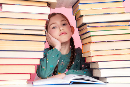 Young girl resting between stacks of book, showcasing the concept of education and study on a...