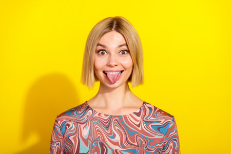 Playful young woman making a funny face in a vibrant background wearing a trendy printed top...