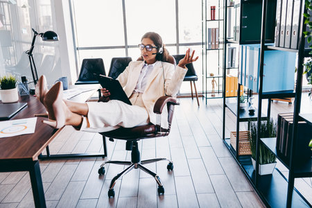 Charming businesswoman working confidently in a modern corporate office space while speaking and multitasking efficiently.の写真素材