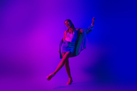 Lovely Young Woman Dancing in Neon Purple and Blue Light Showcasing Style and Energy