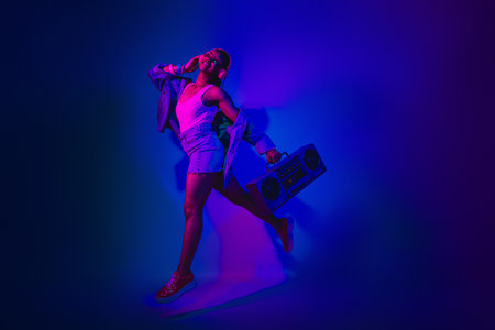 Energetic young woman holding a vintage boombox surrounded by vibrant neon lights in an exciting...