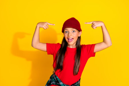 Delightful young girl wearing casual fashion posing with gesturing hands against vibrant yellow background showing excitementの写真素材