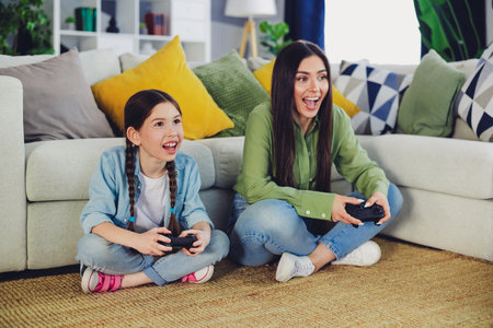 Mom and daughter enjoying video games together in a cozy living room setting, capturing family...