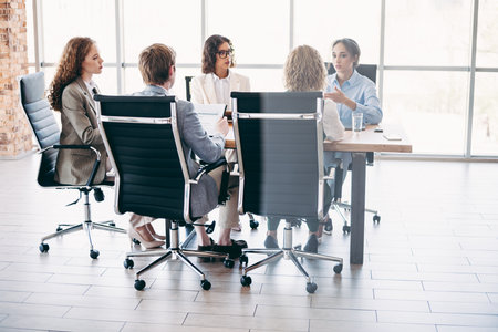 Office team collaborating during a professional meeting in a modern workspace with a team of executives engaged in discussionの写真素材