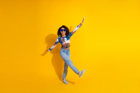 Stylish young woman enjoying leisure time against bright yellow background showcasing fashion and...