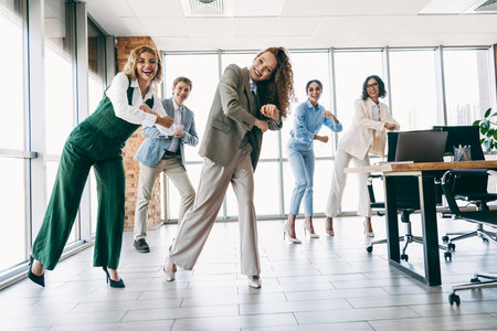 Professional team builds camaraderie through fun group activity in modern office environment emphasizing collaborationの写真素材