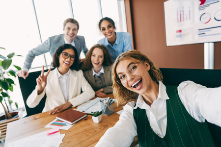 Team of diverse business professionals collaborating together in a modern office workspace, smiling and demonstrating teamworkの写真素材