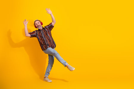 Charismatic mature man with styled beard enjoying music and dancing in excitement against a vibrant...