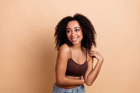 Portrait of a Stylish Young Woman Smiling Confidently Against a Beige Backgroundの写真素材