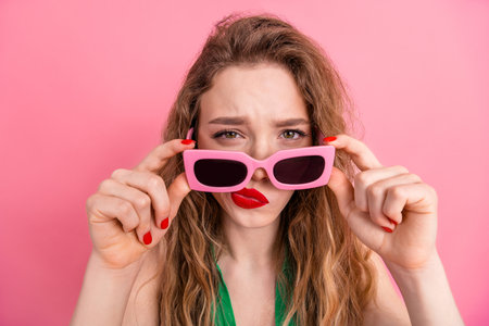 Young fashionable woman in sunglass posing with a vibrant pink background showcasing casual style and expressionの写真素材
