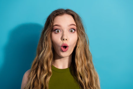 Surprised young woman against a bright background expressing amazement and emotionの写真素材