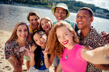 Joyful group of friends on summer vacation taking a selfie by the waterfront under sunny skies