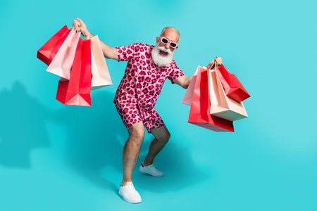 Full body photo of senior bearded man have fun enjoy shopping dressed stylish pink leopard print clothes isolated on cyan color backgroundの写真素材