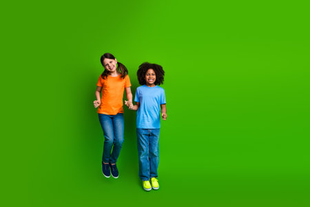 Diverse friends having fun together while smiling joyfully against a vibrant green backdrop during a...