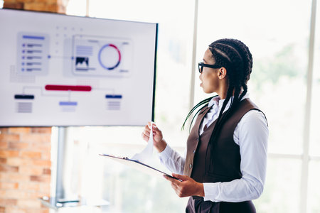 Professional businesswoman delivers a presentation with analytics display in a modern bright office settingの写真素材