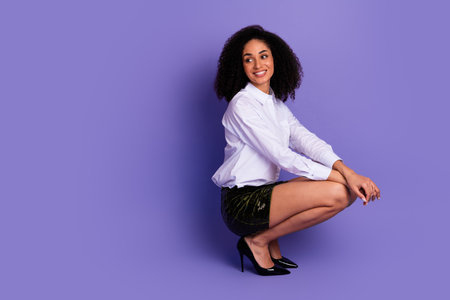 Elegant young woman in stylish formalwear posing confidently against a purple background, showcasing fashion and beautyの写真素材