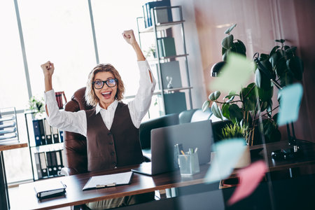 Confident businesswoman rejoicing in modern office with a bright smile and uplifting energy...