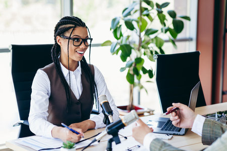 Confident businesswoman conducting workplace discussion in modern office setting with tools for...