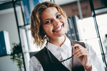 Professional Confident Businesswoman Smiling Indoors at an Office Setting Depicting Career Success and Eleganceの写真素材
