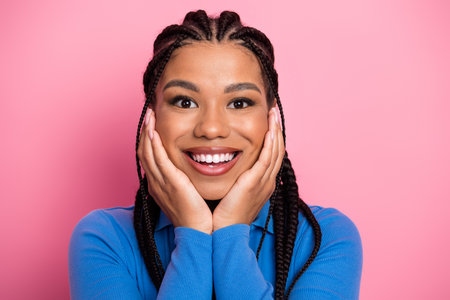 Young woman smiling brightly with her hands on her cheeks against a vibrant pink background