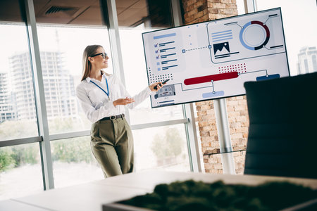 Businesswoman delivering a presentation in a modern office space using data charts for professional...